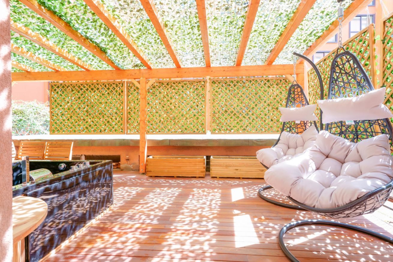 Terrazza esclusiva con veranda in legno, poltrona sospesa e vista su verde lussureggiante: il rifugio perfetto per momenti di puro relax.