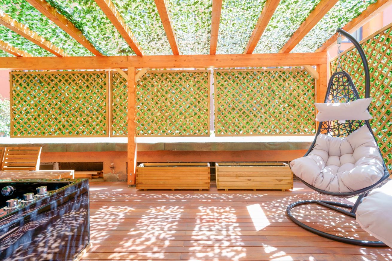 Terrazza esclusiva con pergolato in legno, sedute confortevoli e pareti verdi: il vostro rifugio privato per momenti di puro relax.