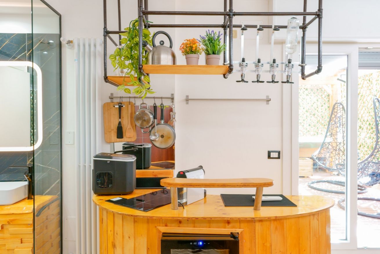 Angolo cottura elegante con bancone in legno, attrezzature moderne e ripiani organizzati, perfetto per soggiorni indipendenti con vista sulla terrazza privata.