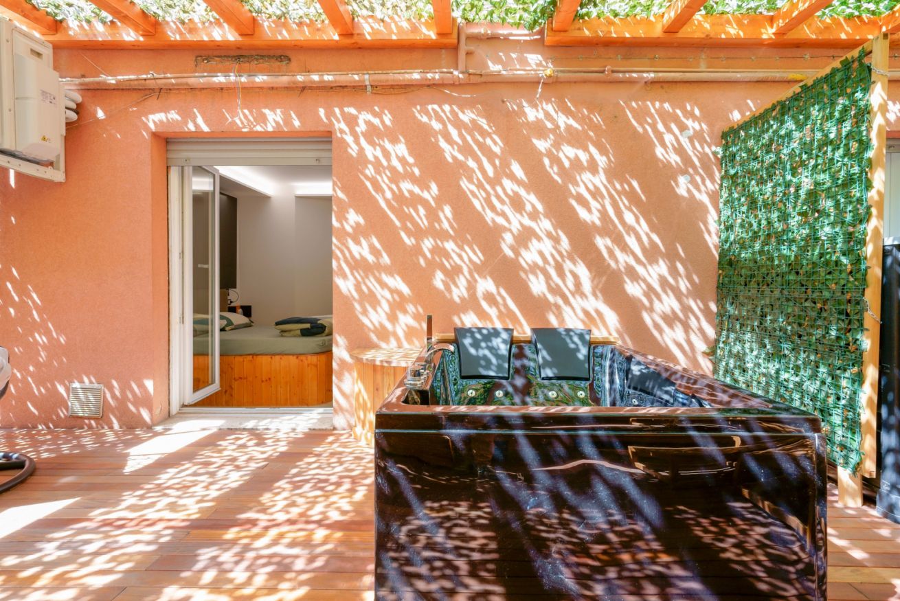 Terrazza privata inondato di sole naturale, con pergolato in legno e vegetazione rigogliosa; lo spazio perfetto per momenti di relax esclusivi.