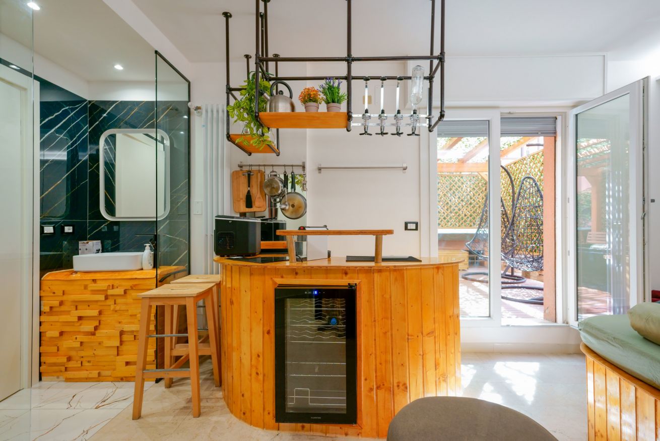 Spazio open-space con elegante arredo in legno: cucina moderna, bagno esclusivo con doccia, e accesso diretto alla terrazza privata.