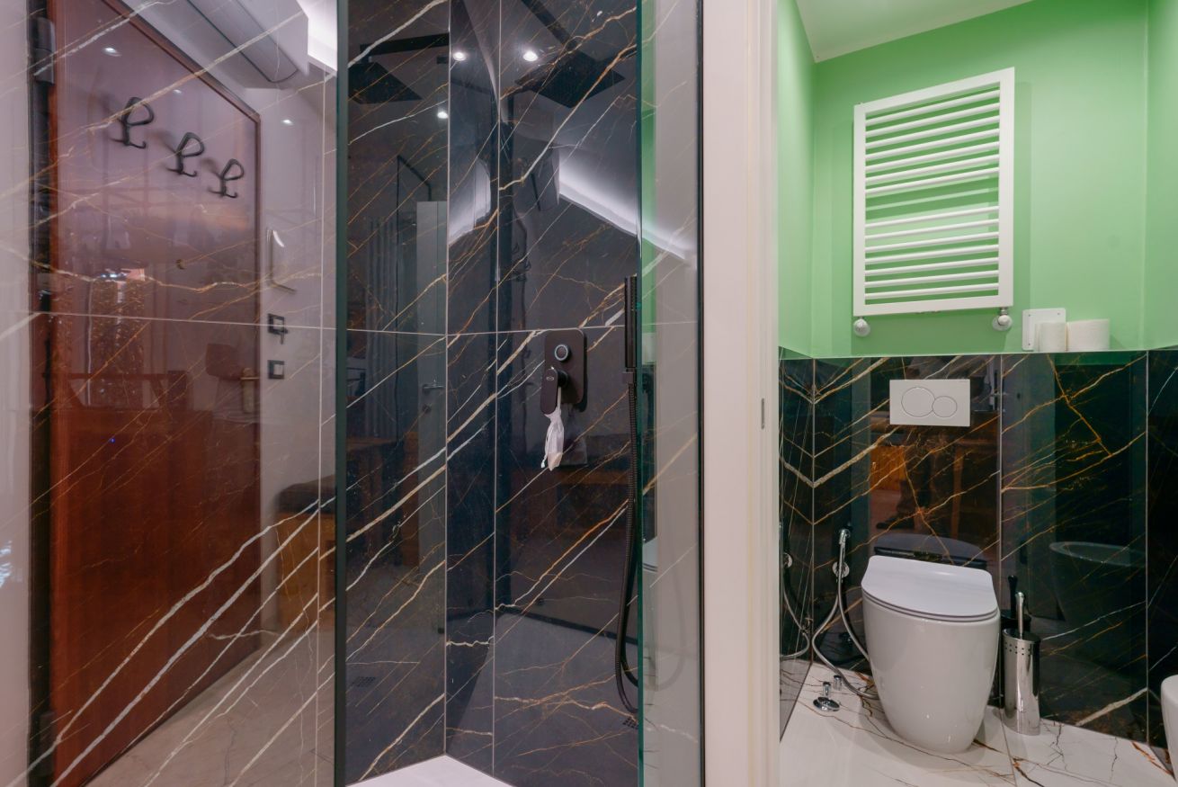 Bagno elegante con rivestimenti in marmo verde e nero, dotato di moderni servizi e dettagli raffinati per il vostro comfort.