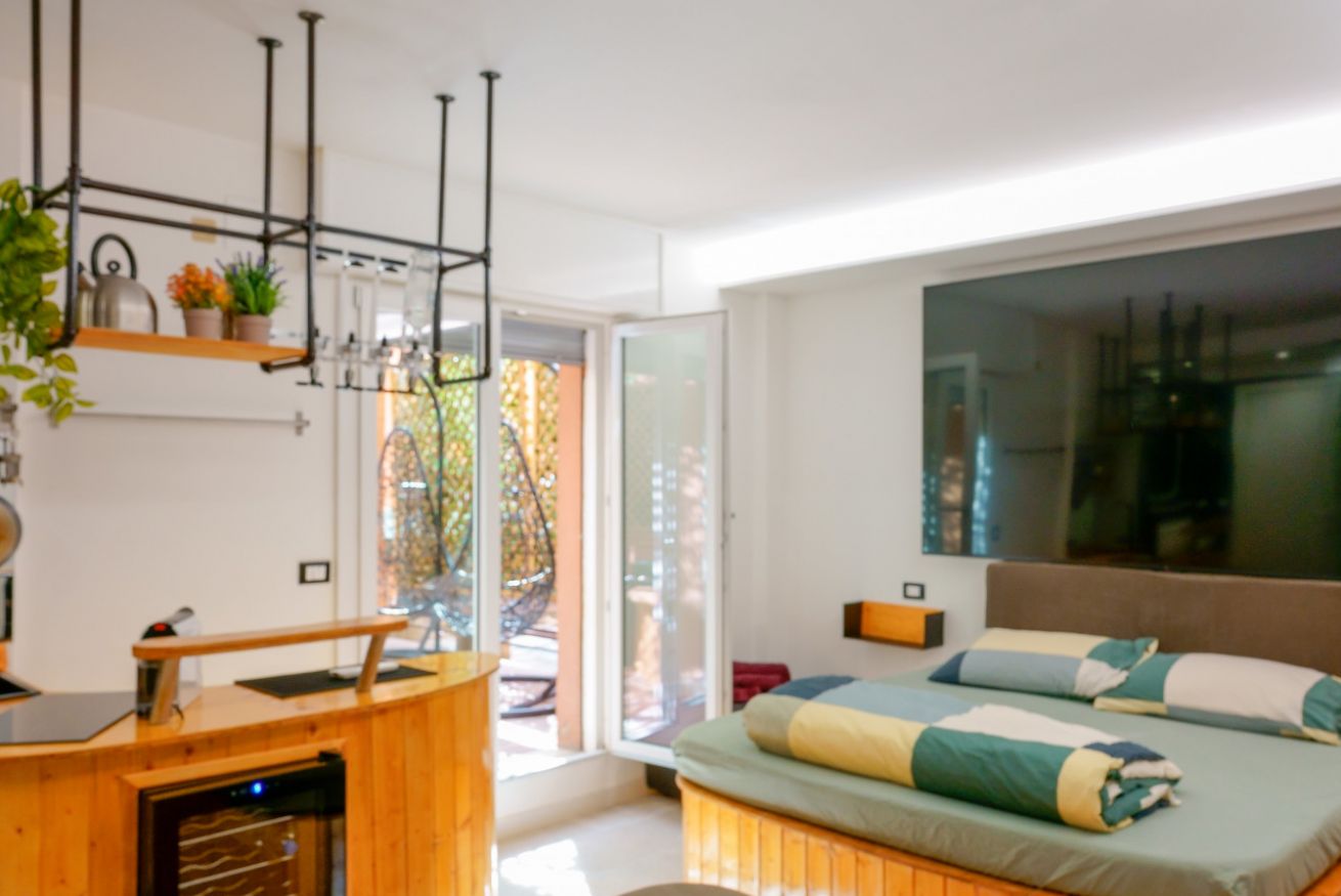 Ambiente luminoso e sofisticato con letto matrimoniale confortevole, angolo cottura in legno e accesso diretto alla terrazza privata.