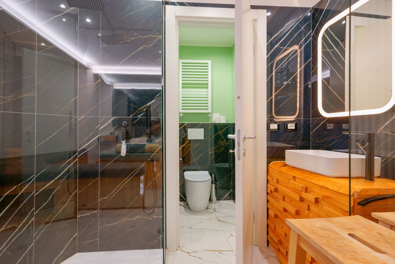 Bagno elegante con finiture marmorizzate, specchi illuminati e dettagli in legno caldo, garantendo comfort e lusso nella vostra permanenza.
