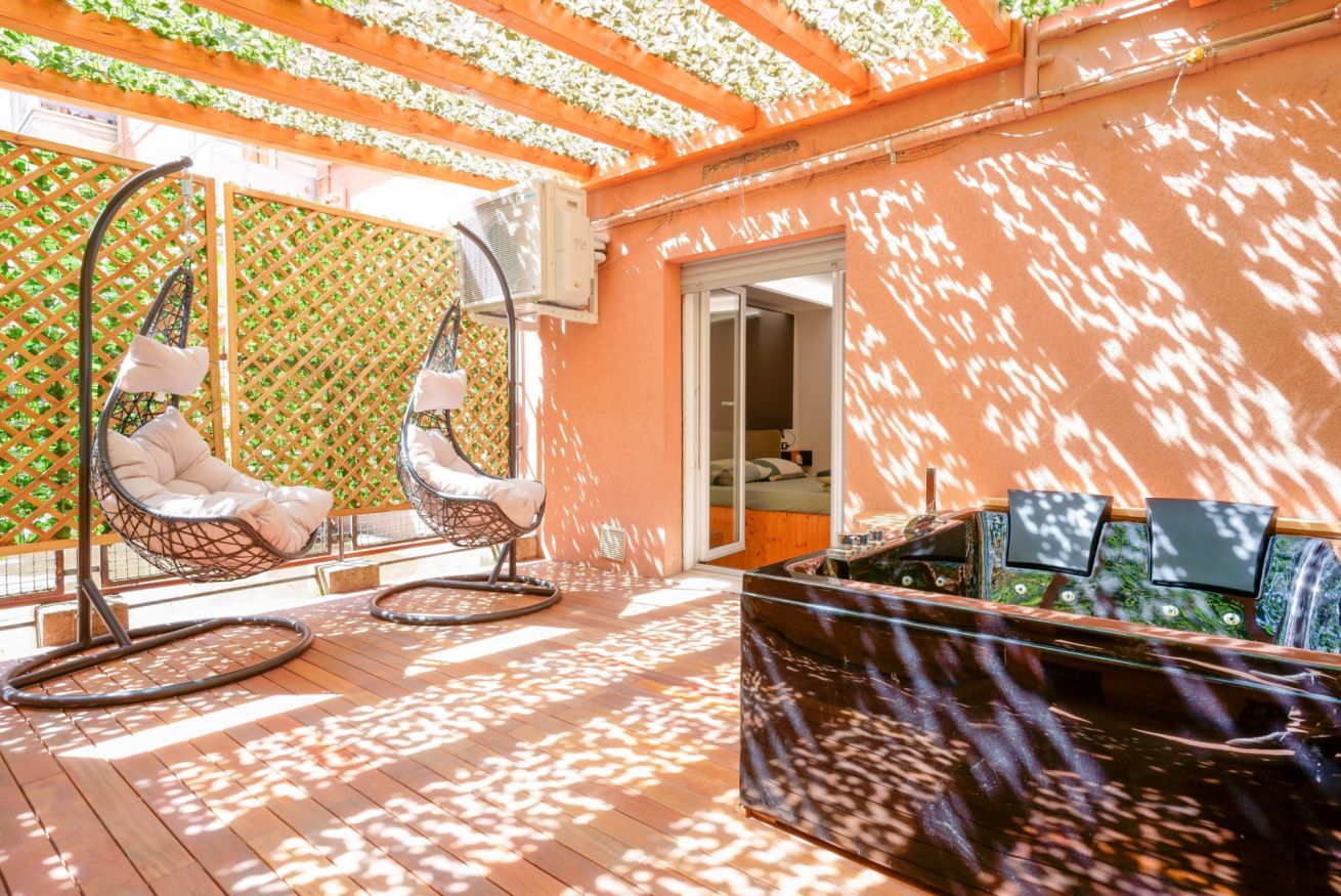 Terrazza privata baciata dal sole con amache sospese, pergolato in legno e vista sulla città: il rifugio perfetto per rilassarsi.