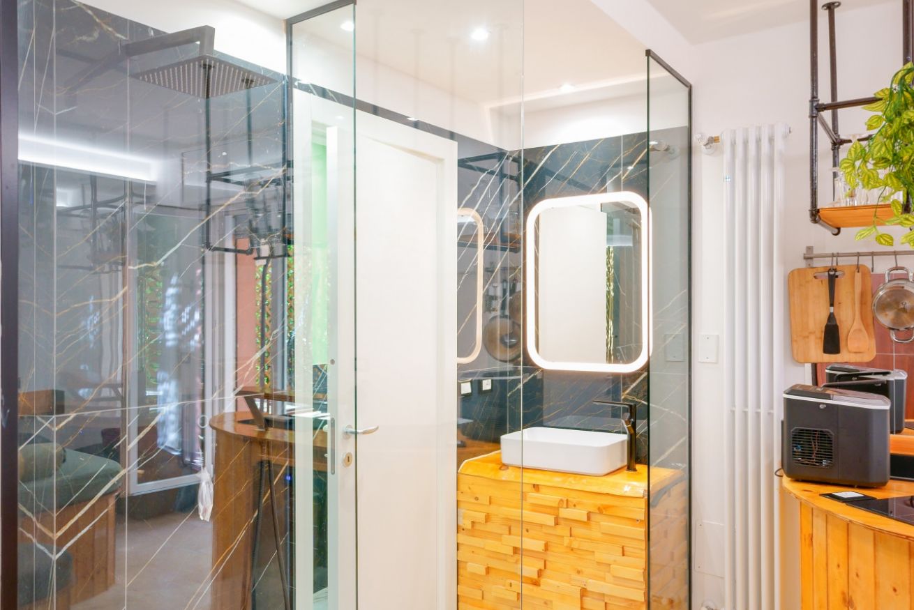 Bagno elegante con vanity illuminato e rivestimenti in marmo, che riflette il comfort e la raffinatezza della Camera Deluxe Amendola 17.
