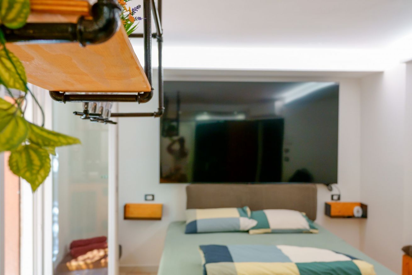 Camera matrimoniale luminosa con letto confortevole, specchio a parete e accenti arancioni che creano un'atmosfera accogliente e moderna.