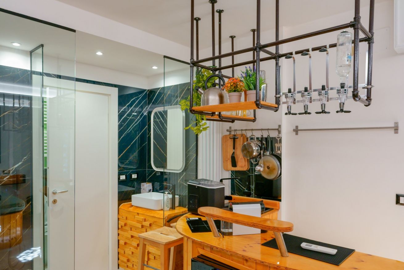 Bagno raffinato con finiture in marmo scuro, specchio a parete, lampade sospese in stile contemporaneo e dettagli in legno naturale.