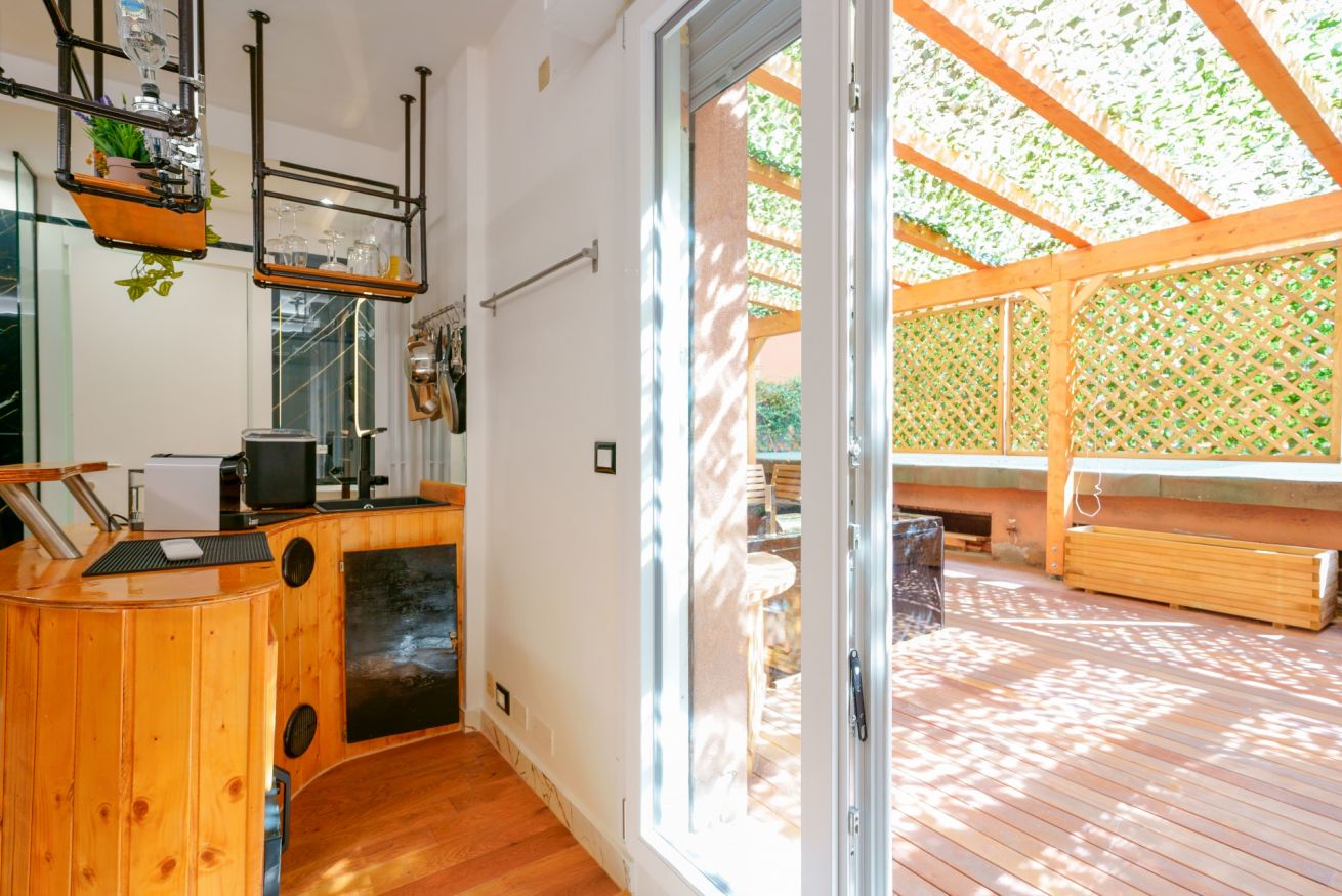 Elegante spazio con zona living in legno naturale e accesso diretto alla terrazza privata, perfetto per momenti di relax all'aperto.