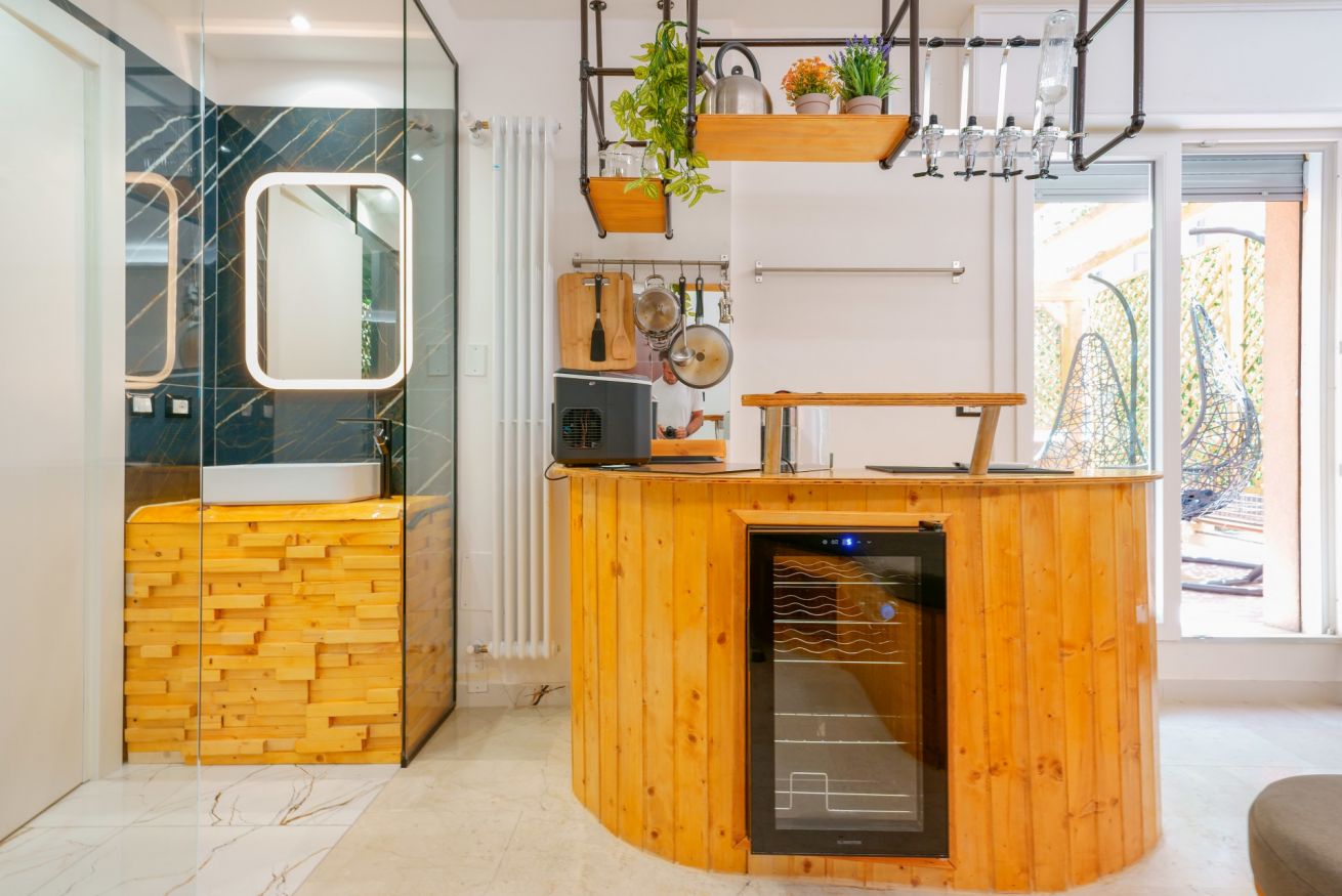 Spazio aperto con angolo cottura in legno caldo, bagno con doccia moderna e dettagli curati: design contemporaneo che unisce funzionalità e comfort.