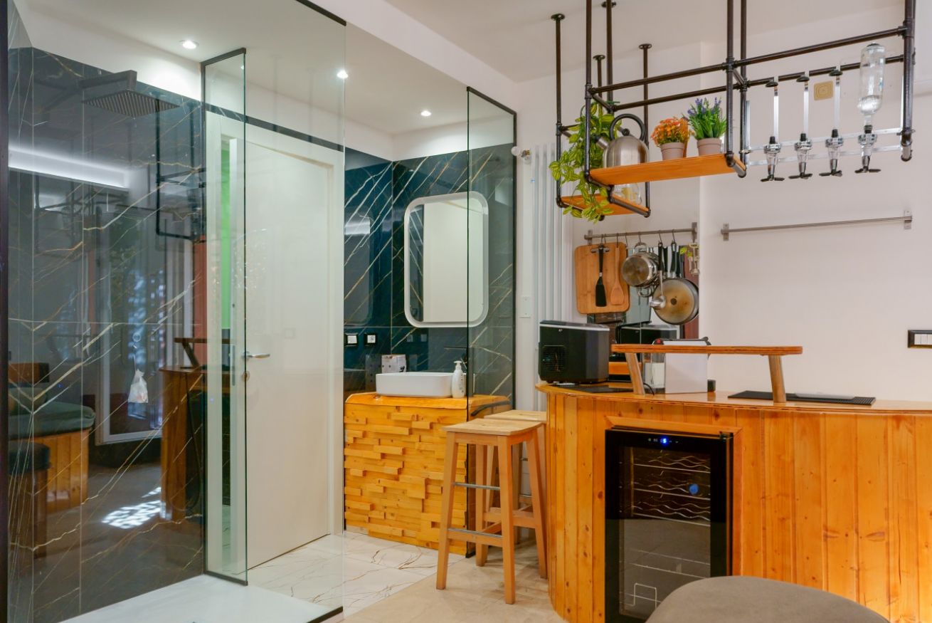 Bagno en-suite elegante con doccia walk-in, rivestimenti in marmo verde e legno caldo, complementato da arredi in legno naturale e dettagli in arancio.