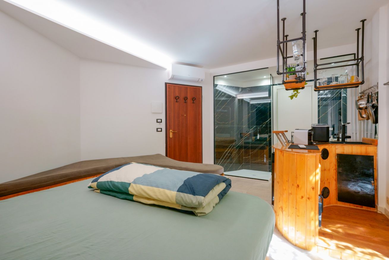 Luminosa camera matrimoniale con letto confortevole, arredo essenziale in legno e accesso alla terrazza privata per godere della vista esterna.