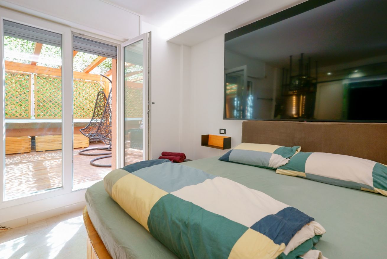 Camera matrimoniale luminosa con elegante arredamento, accesso diretto alla terrazza privata e vista sulla corte interna. Comfort e serenità in ogni dettaglio.