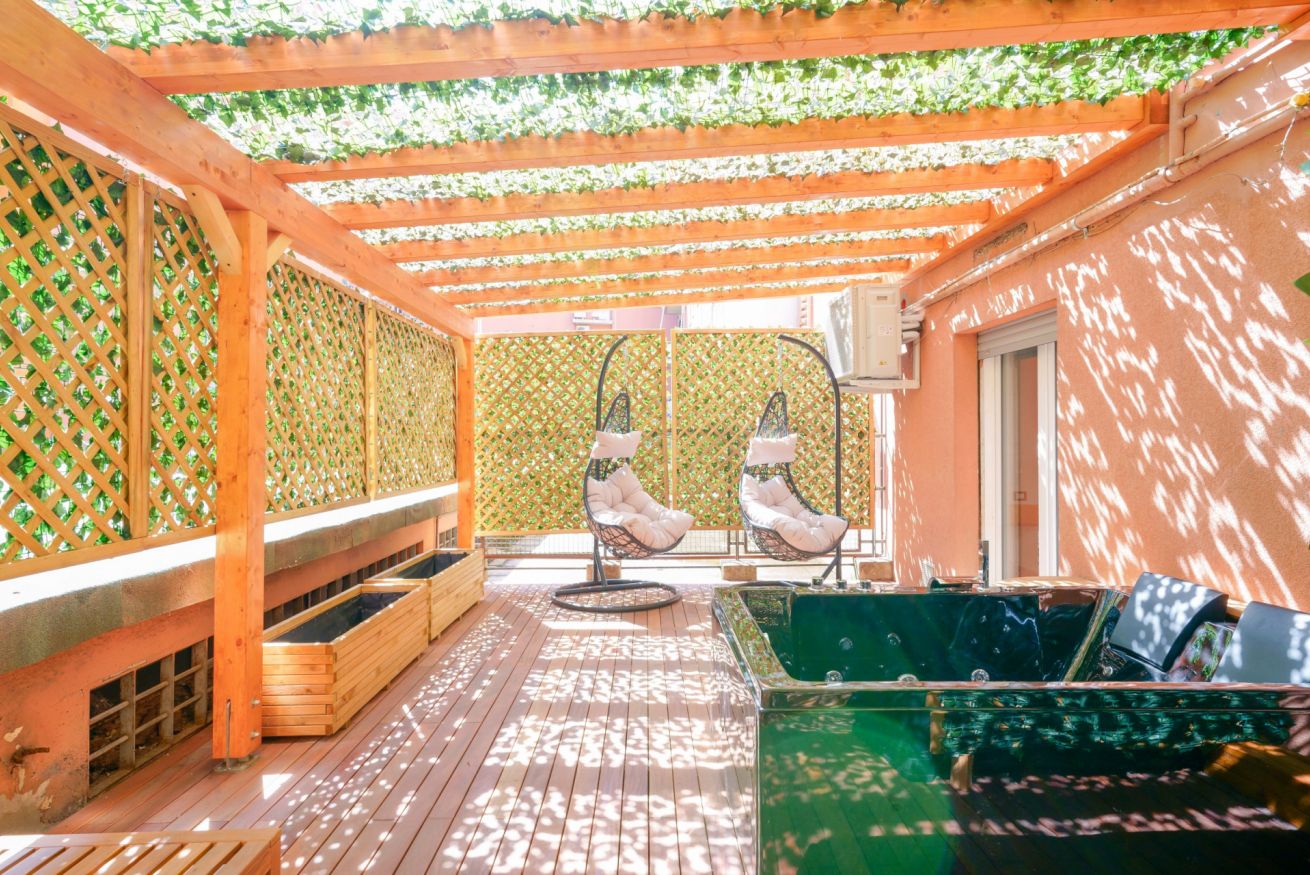 Terrazza privata esclusiva con pergolato in legno, sedute confortevoli e vista sulla verdeggiante corte interna, l'oasi perfetta per momenti di relax.