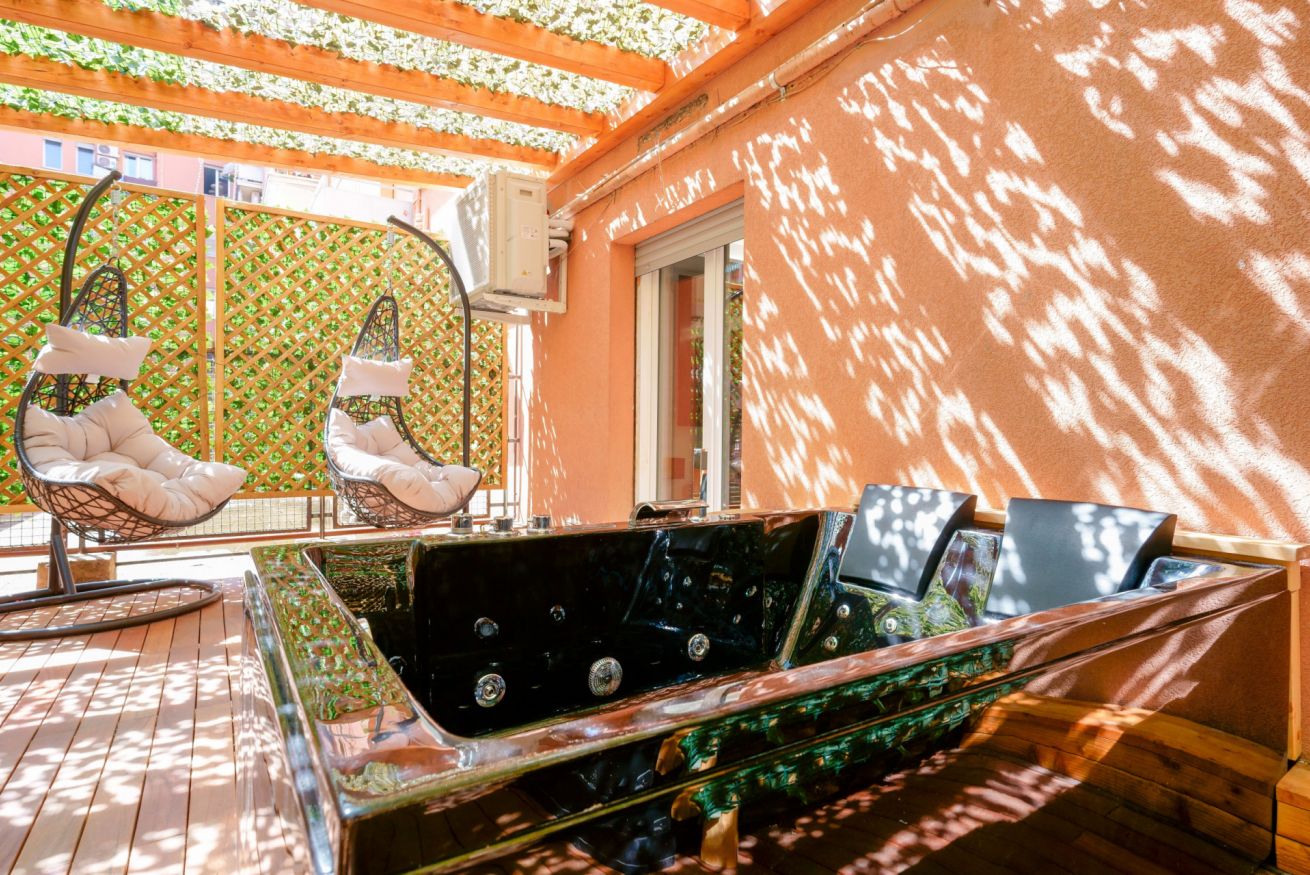 Terrazza privata con vasca idromassaggio, lettini sospesi e pergolato ombreggiato: il rifugio perfetto per relax esclusivo sotto il sole.
