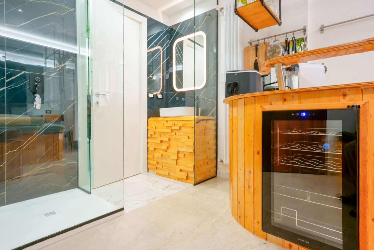 Bagno lussuoso con doccia walk-in, mobile in legno caldo e moderna vanity illuminata, perfetto rifugio di relax nella Camera Deluxe.