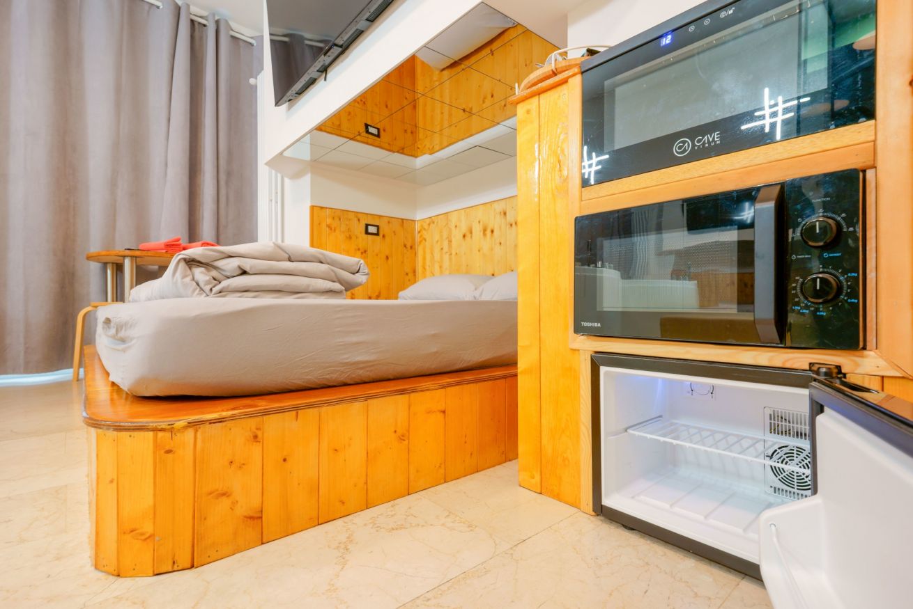 Camera in legno massiccio con letto matrimoniale rialzato, angolo cottura e moderne dotazioni per il massimo comfort e relax.