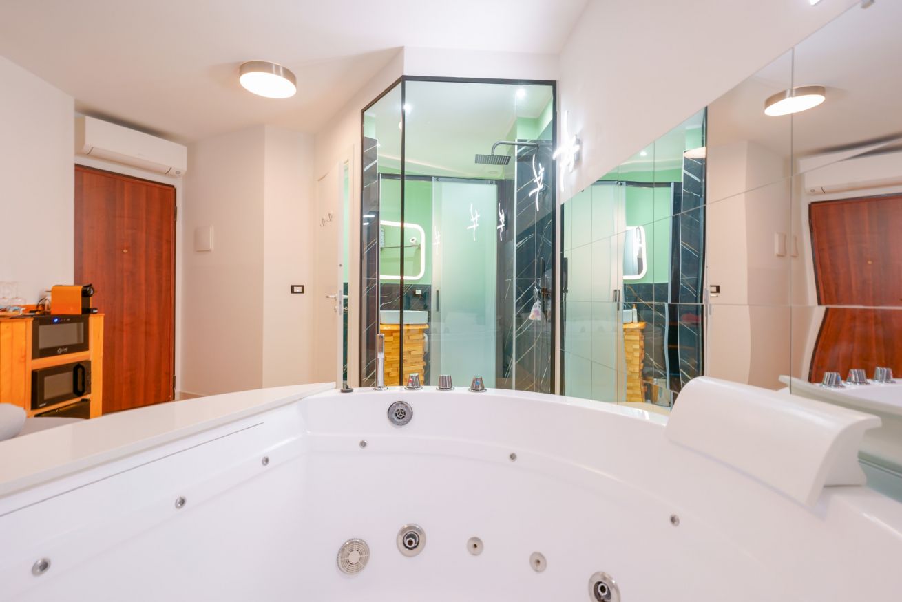 Lussuosa vasca idromassaggio a 2 posti con doccia walk-in in vetro, bagno moderno e luminoso per un relax esclusivo nella vostra camera.