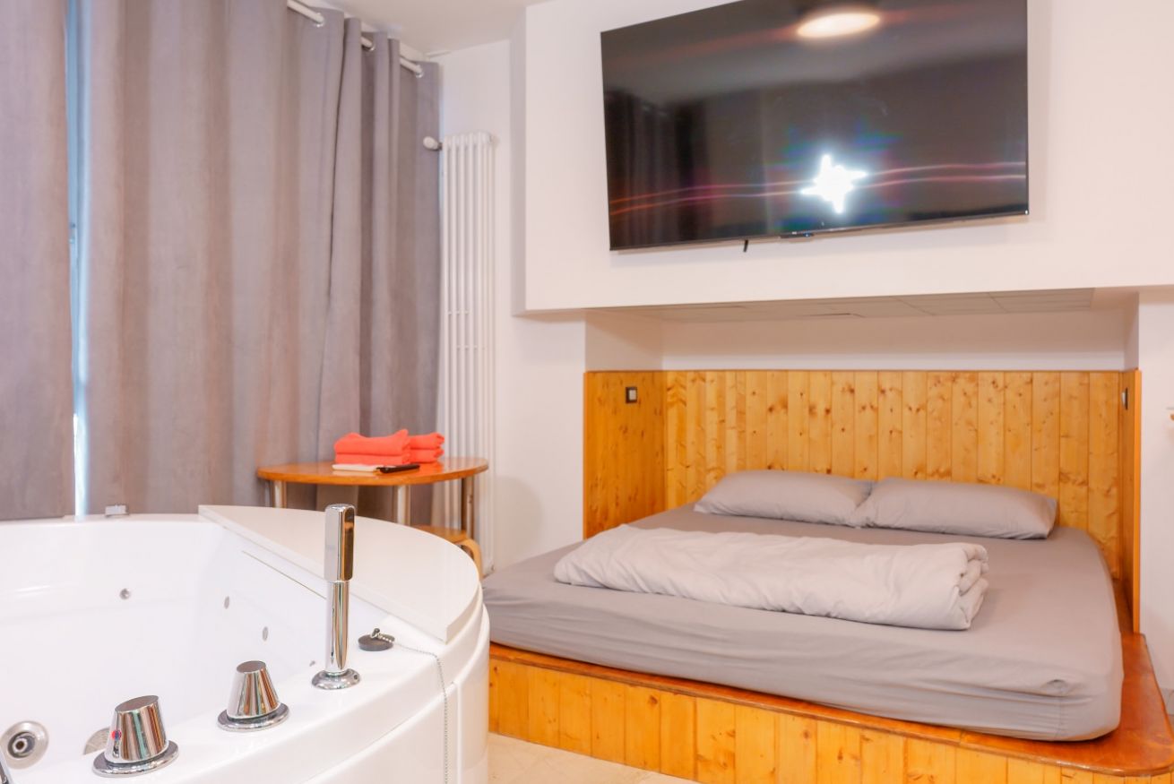 Camera accogliente con letto matrimoniale in legno e vasca idromassaggio privata, perfetta per un relax a due.