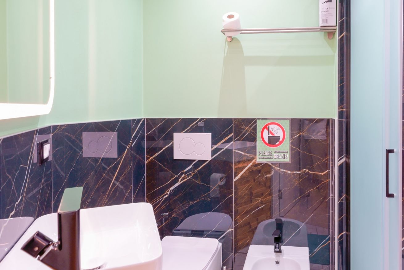 Bagno elegante con rivestimenti in marmo nero, specchio illuminato e accessori di qualità in una camera pensata per il comfort di coppia.