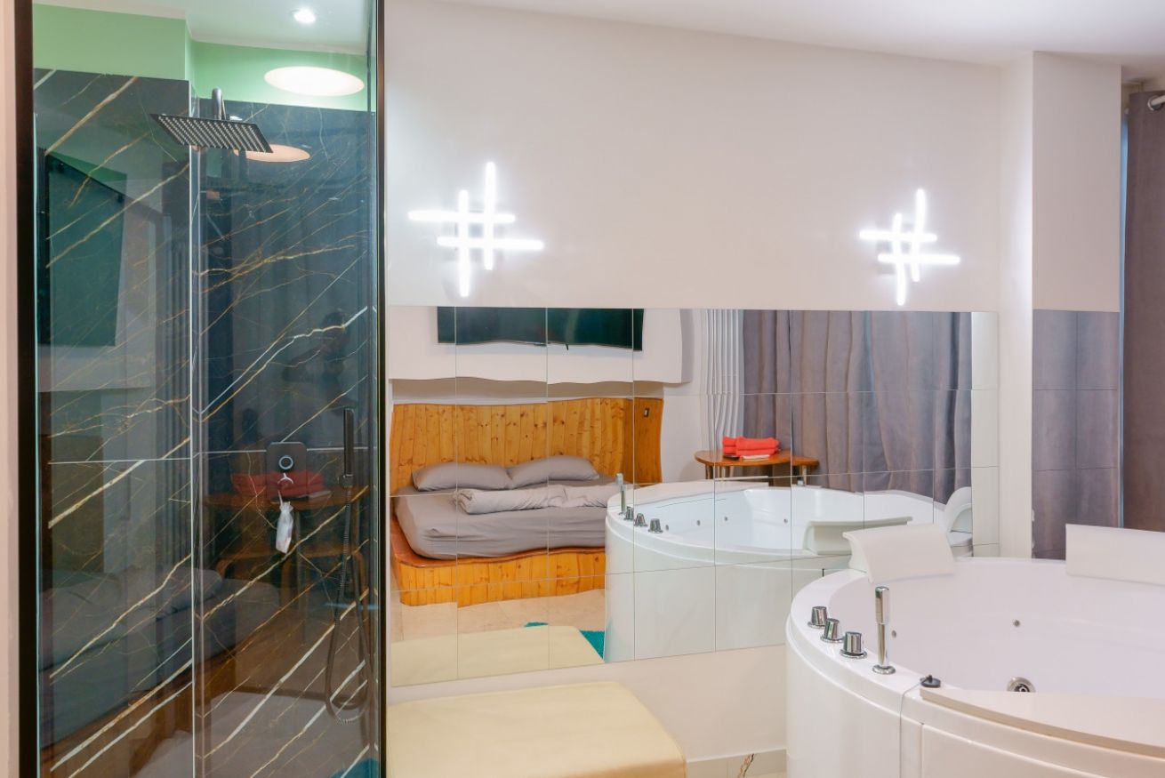 Camera matrimoniale elegante con vasca idromassaggio a 2 posti, doccia walk-in e ampi spazi luminosi per un soggiorno all'insegna del benessere.