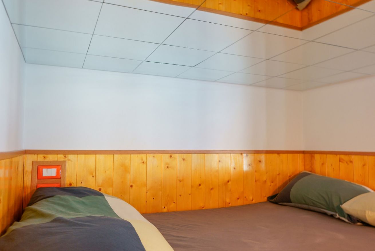 A welcoming room with single beds, natural wood finishings, and wooden ceilings: an intimate and characterful space for your stay.