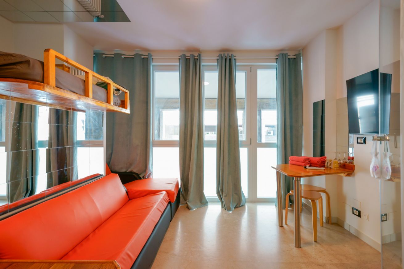 Bright room with an orange sofa, panoramic windows overlooking the city, modern furnishings and well-organized spaces for your comfort.