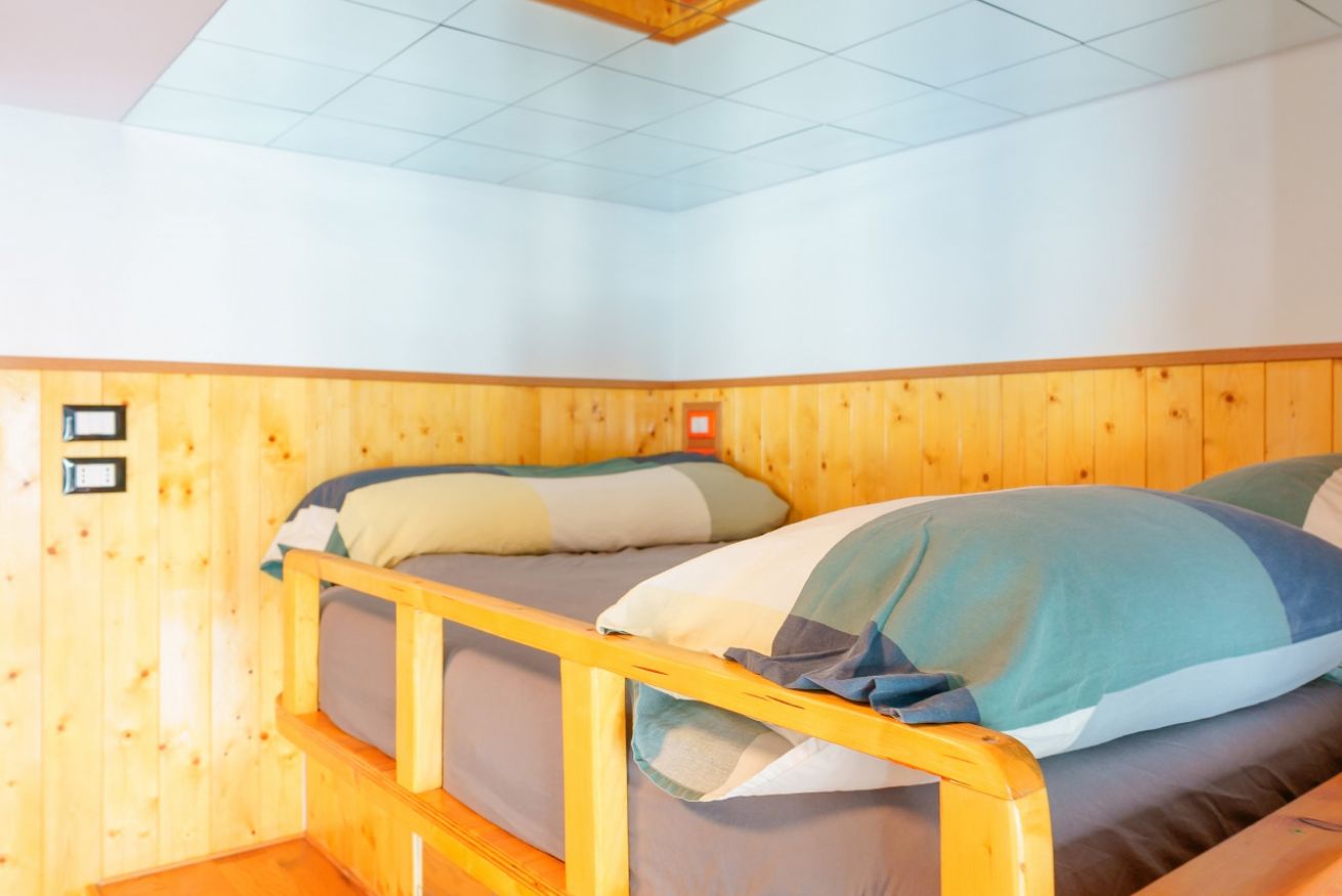 Camera accogliente rivestita in legno naturale, con letto confortevole e biancheria fresca, perfetta per un soggiorno sereno e rilassante.